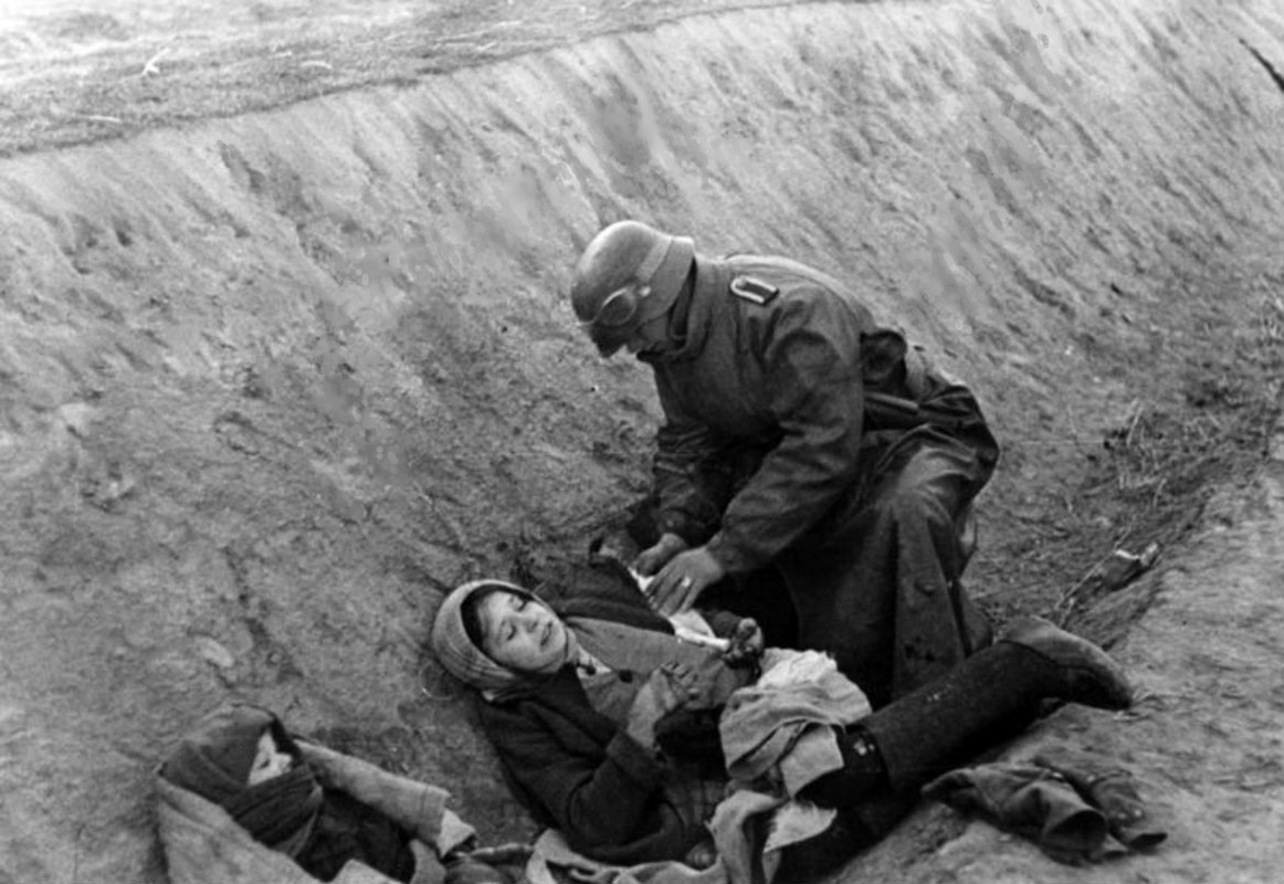 Soldado alemán atiende a una mujer rusa herida junto a su bebé en una trinchera alemana