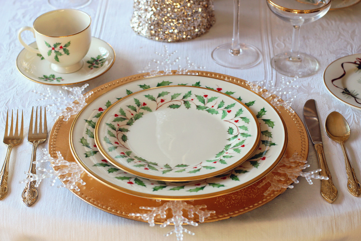 An elegant dining set-up with holly patterned plates, teacup, and saucer.